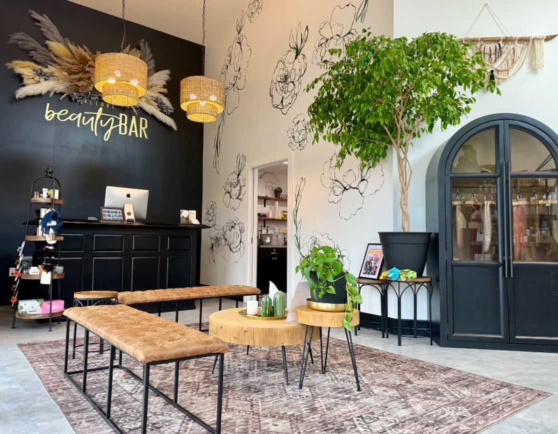 Stylish salon interior with rustic decor, black counter, hanging lights, and floral wall art.
